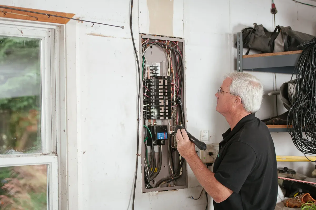 Elektryk sprawdzający domową rozdzielnicę podczas zajęć praktycznych kursu